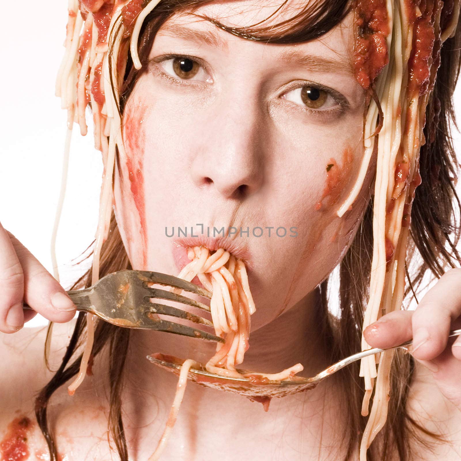 Red haired girl with a meal of spaghetti on her head eating