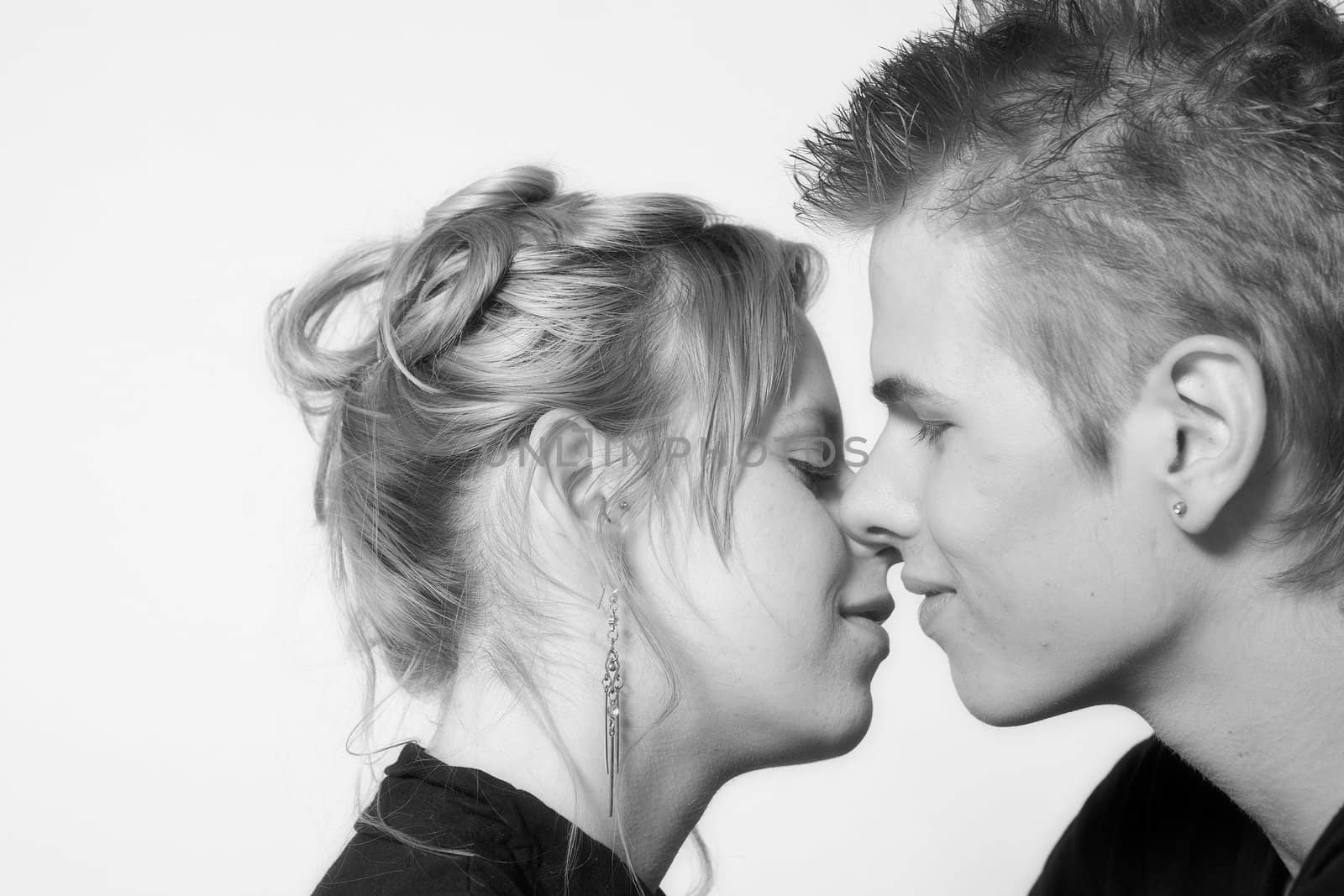 Couple of teenagers in the studio on a white background kissing
