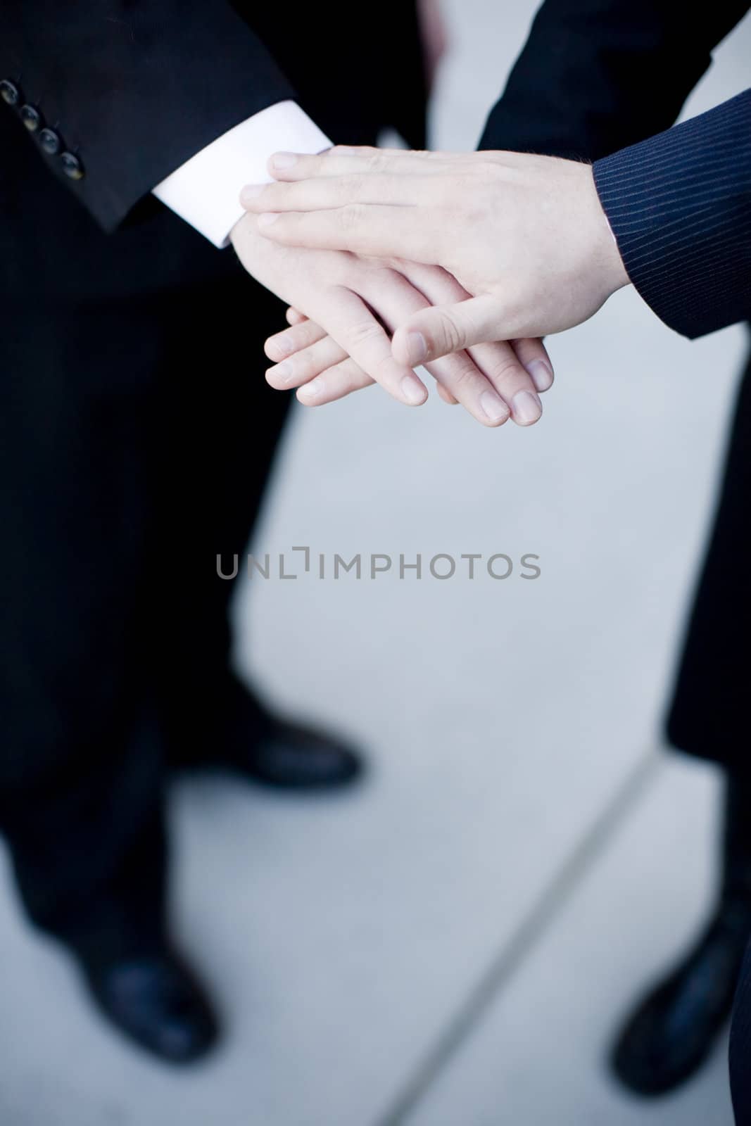 close up of three businesspeople placing hands on one another