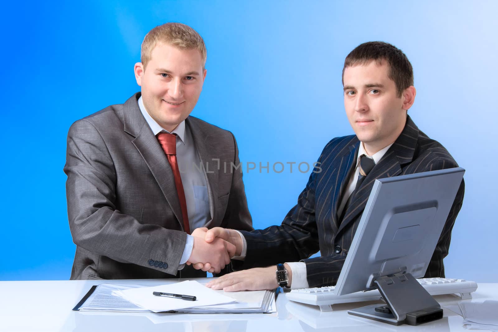 Two young handsome business men shake hands each other