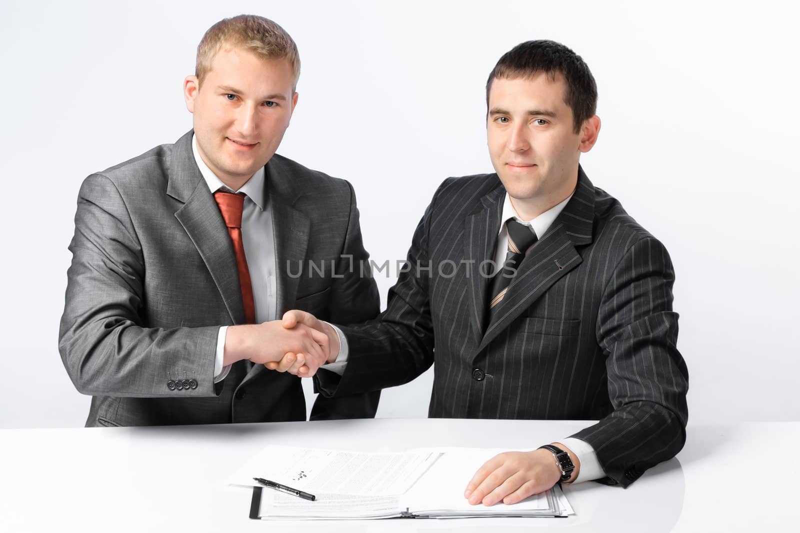 Two young handsome business men shake hands each other