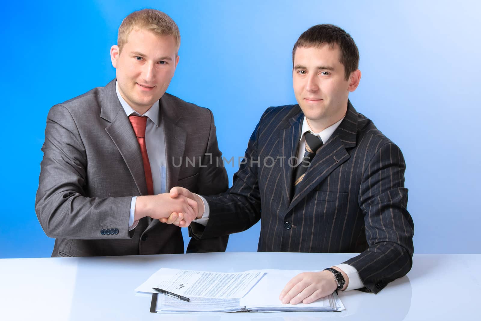 Two young handsome business men shake hands each other