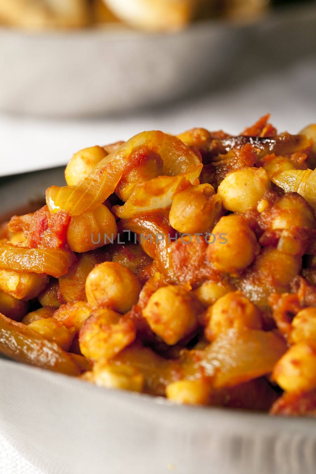 Fresh tomato and chickpea curry in metal bowl.