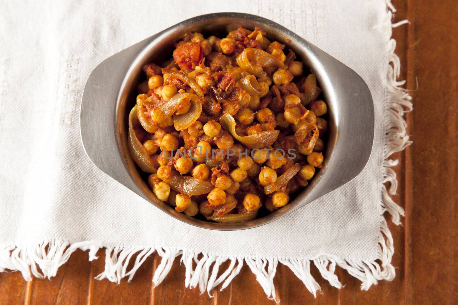 Fresh tomato and chickpea curry in metal bowl shot from directly above.
