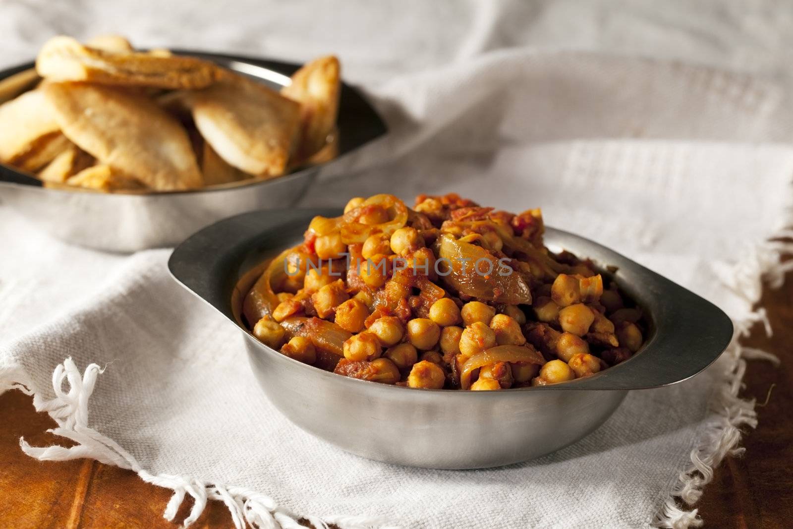 Fresh tomato and chickpea curry in metal bowl.