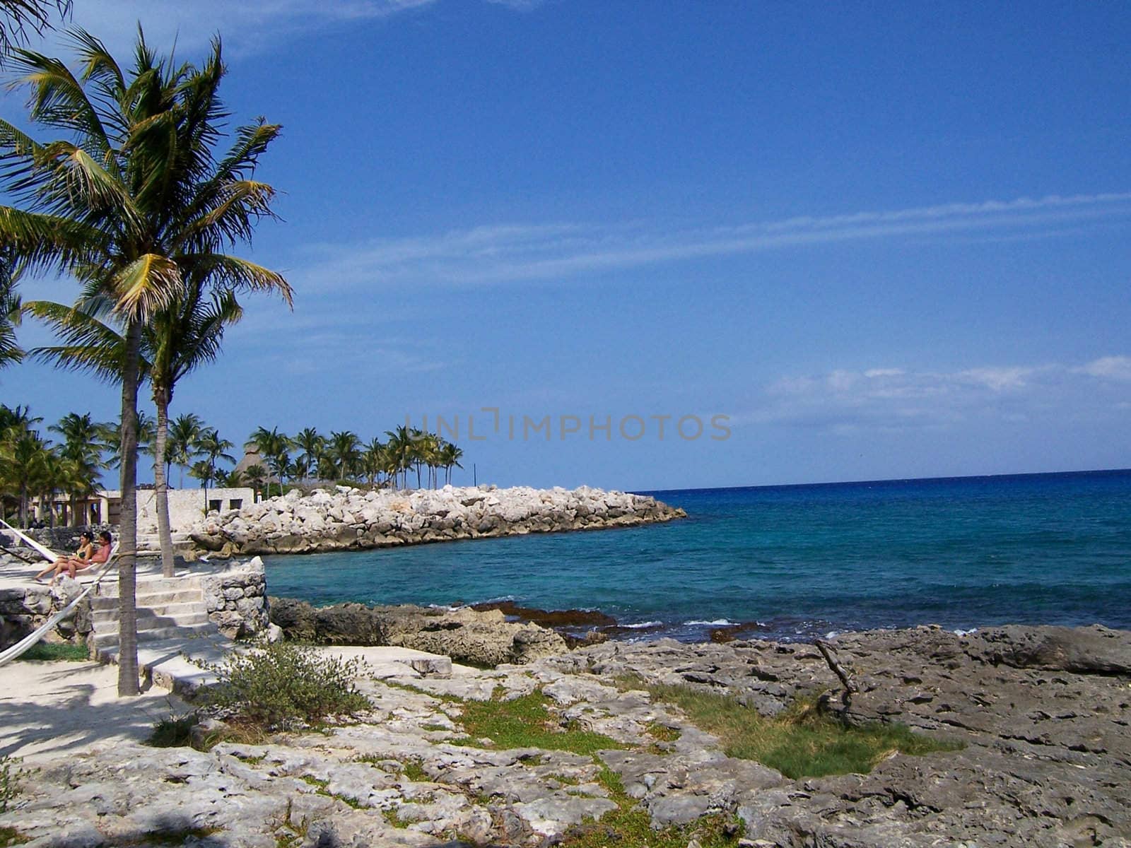 Mexican beach at Yucatan Peninsula with trees, rocks and hammocks.