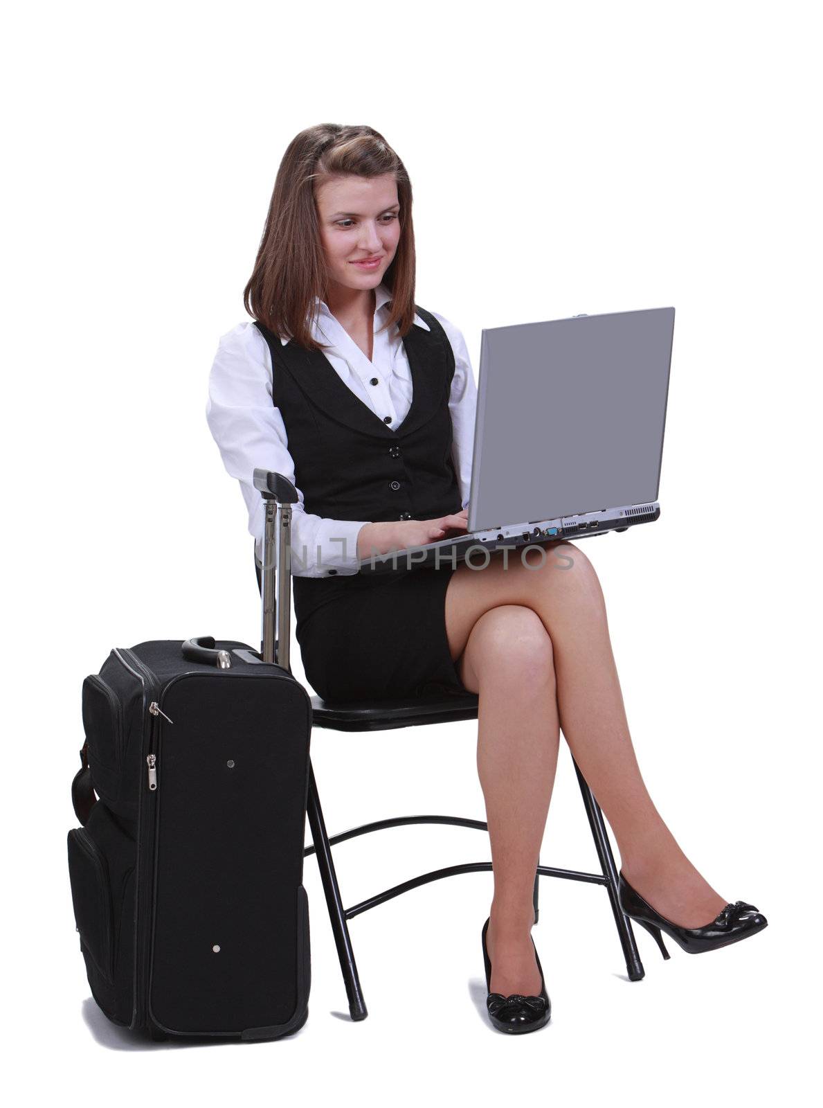 Young woman traveler working in a hurry on the latop next to her suitcase- isolated against a white background.