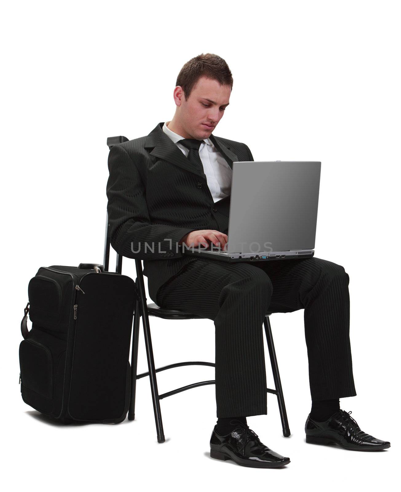 Young traveler businessman working on a laptop next to his suitcase.