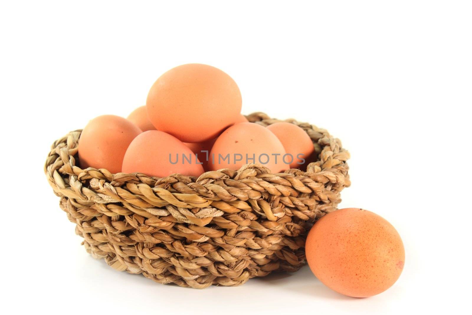 Fresh raw eggs in a basket on a white background