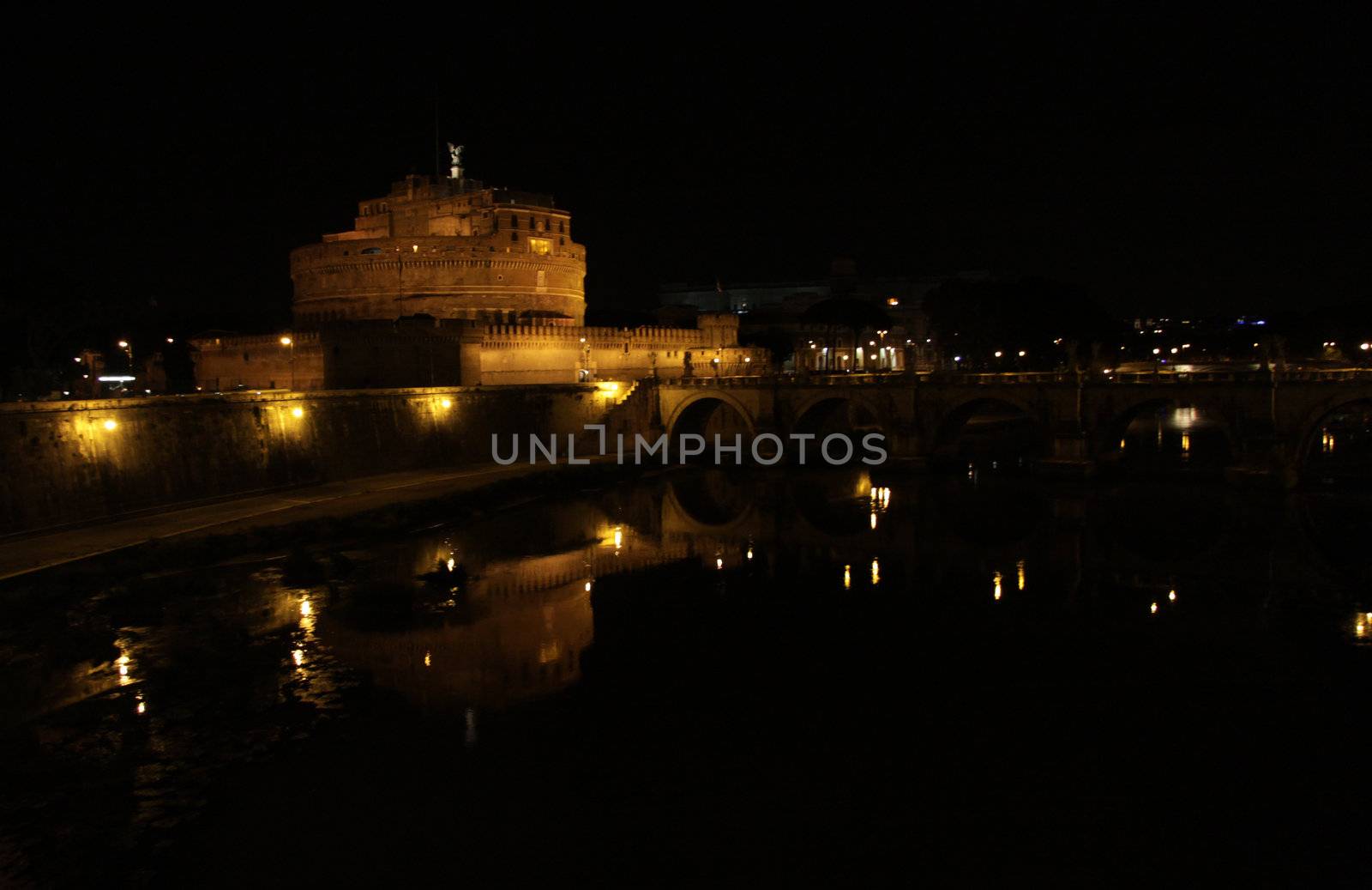 The towering Castel Sant'Angelo (Mausoleum of Hadrian) in Rome, Italy.  Shot at night from across the Tiber river.
