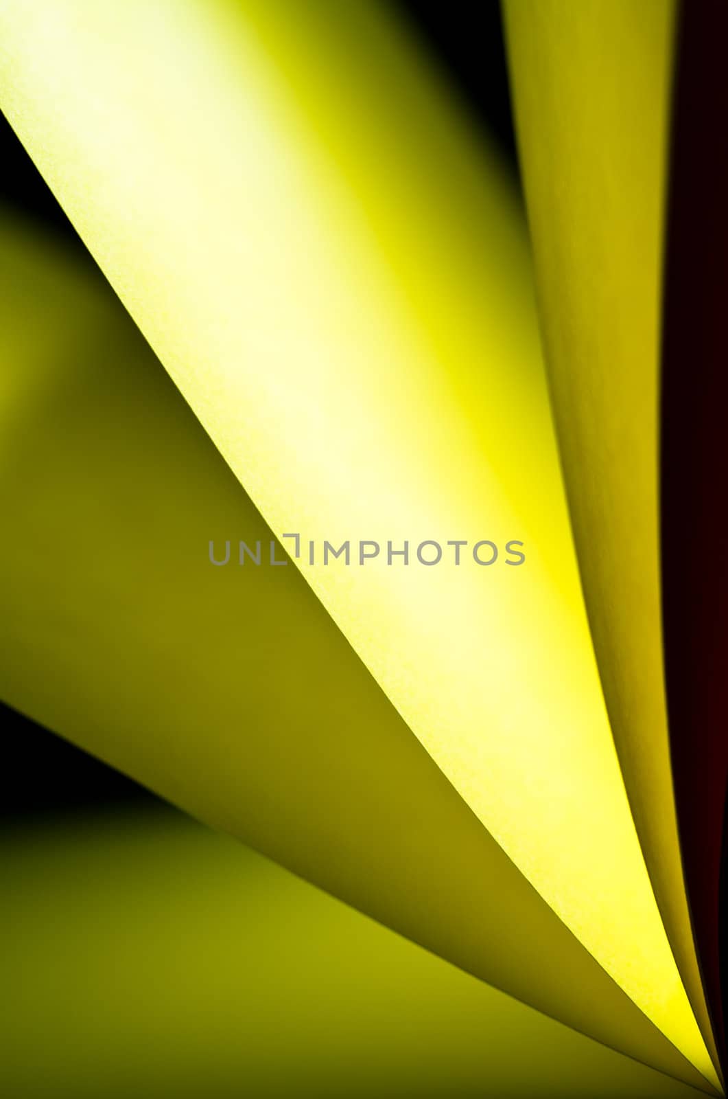 Yellow notepad paper illuminated by LED light with black background in portrait orientation with the paper from lower right angle
