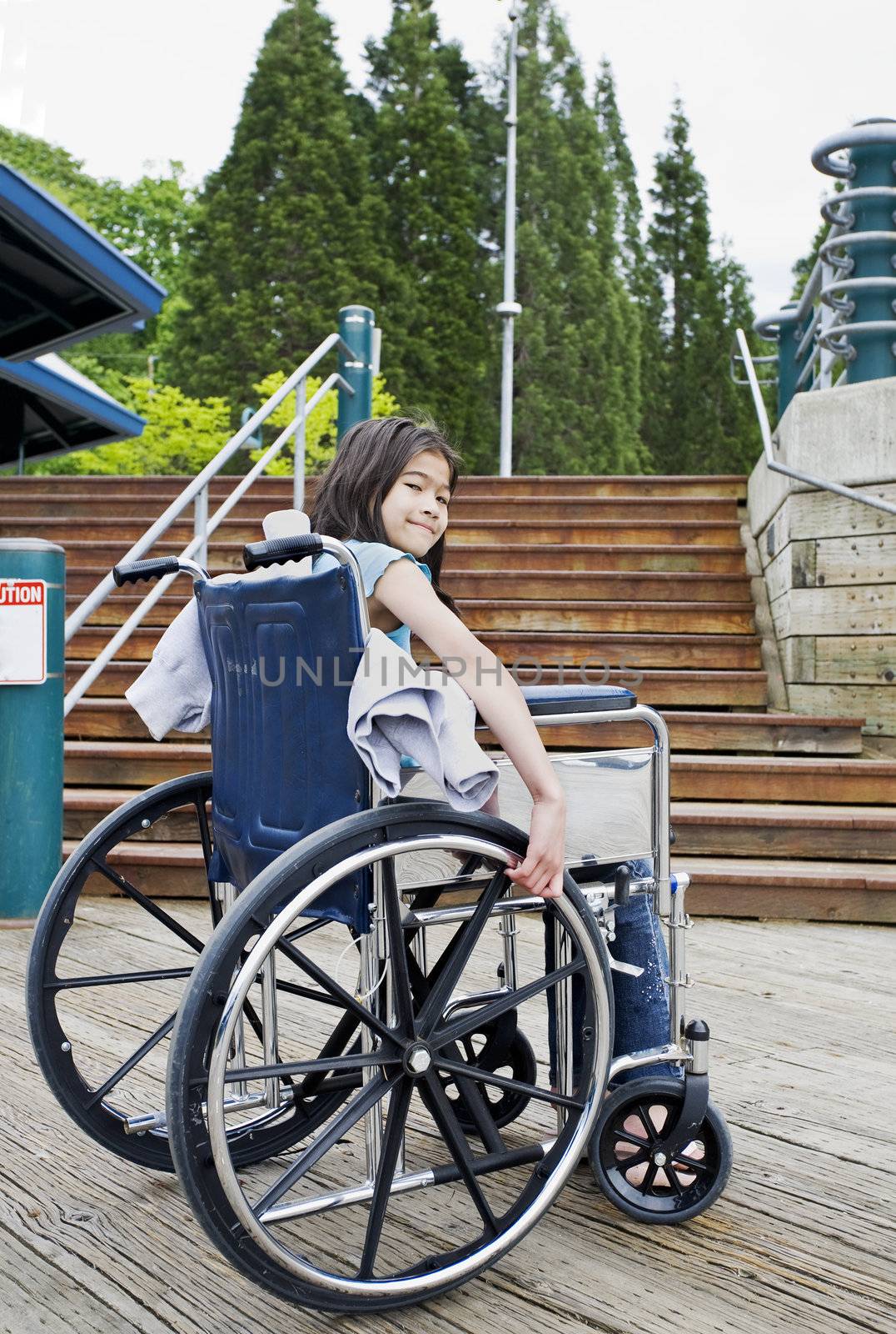 Young nine year old girl in wheelchair in front of stairs