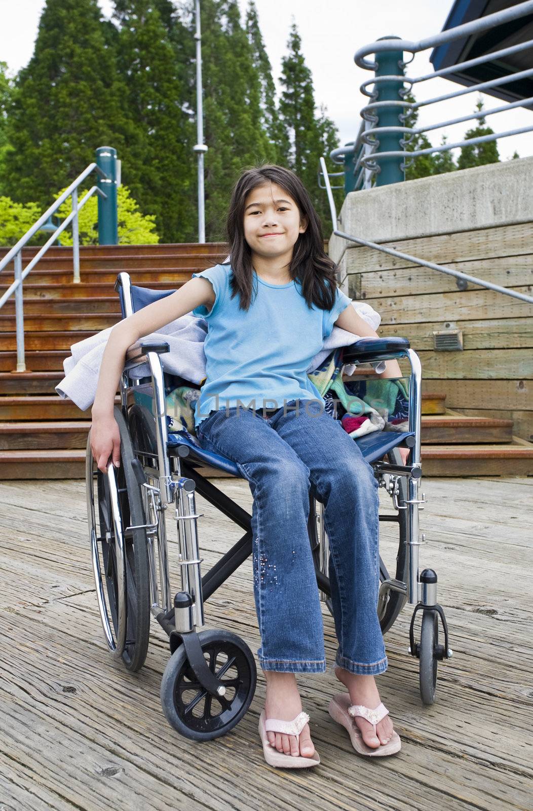 Young nine year old girl in wheelchair in front of stairs