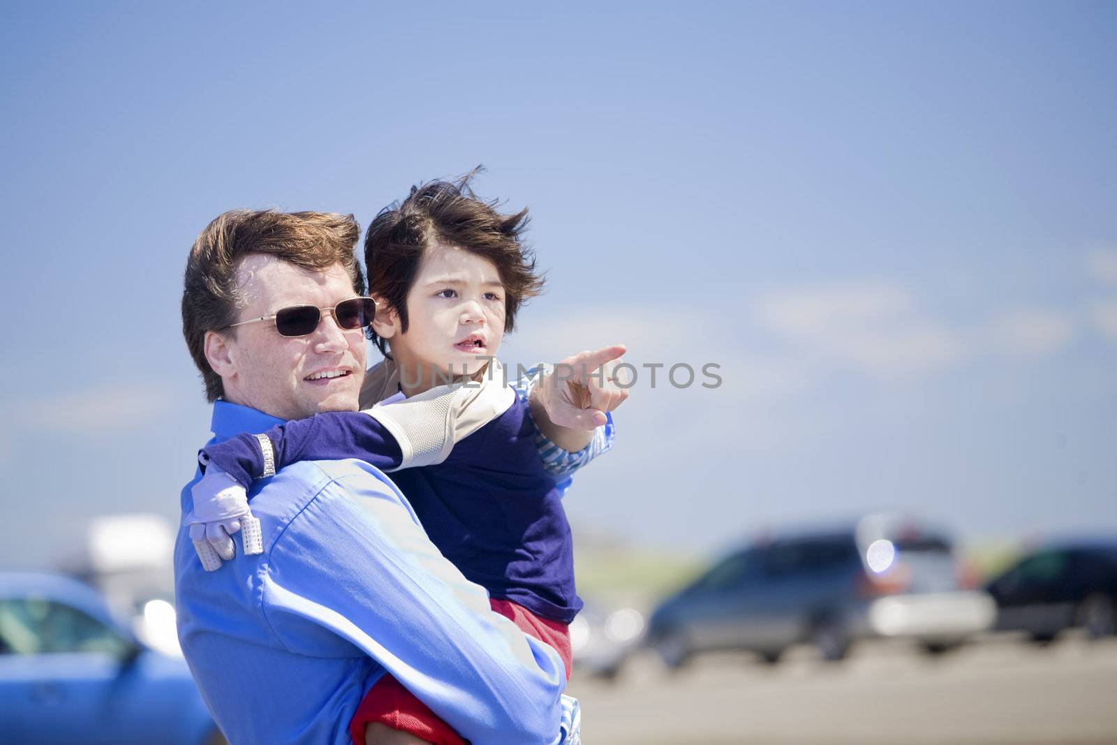 Father holding disabled son on the beach, pointing to something on the side