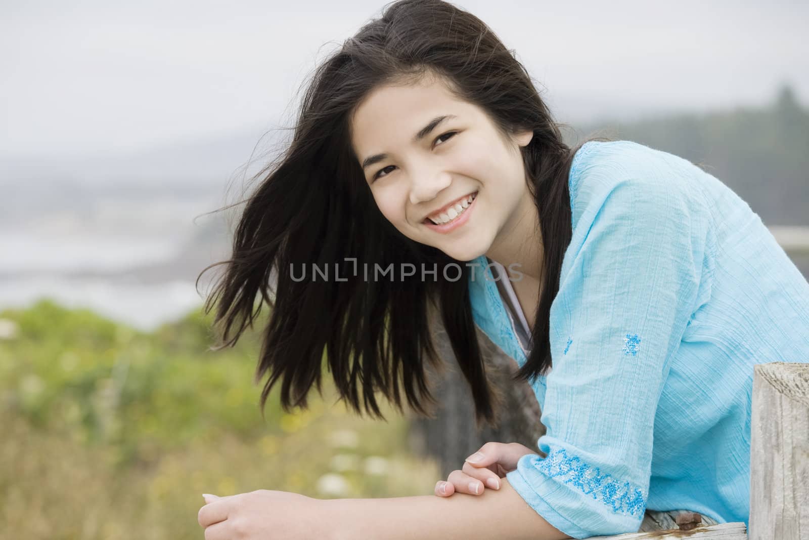 Preteen biracial girl with a beautiful smile, overlooking the ocean shore