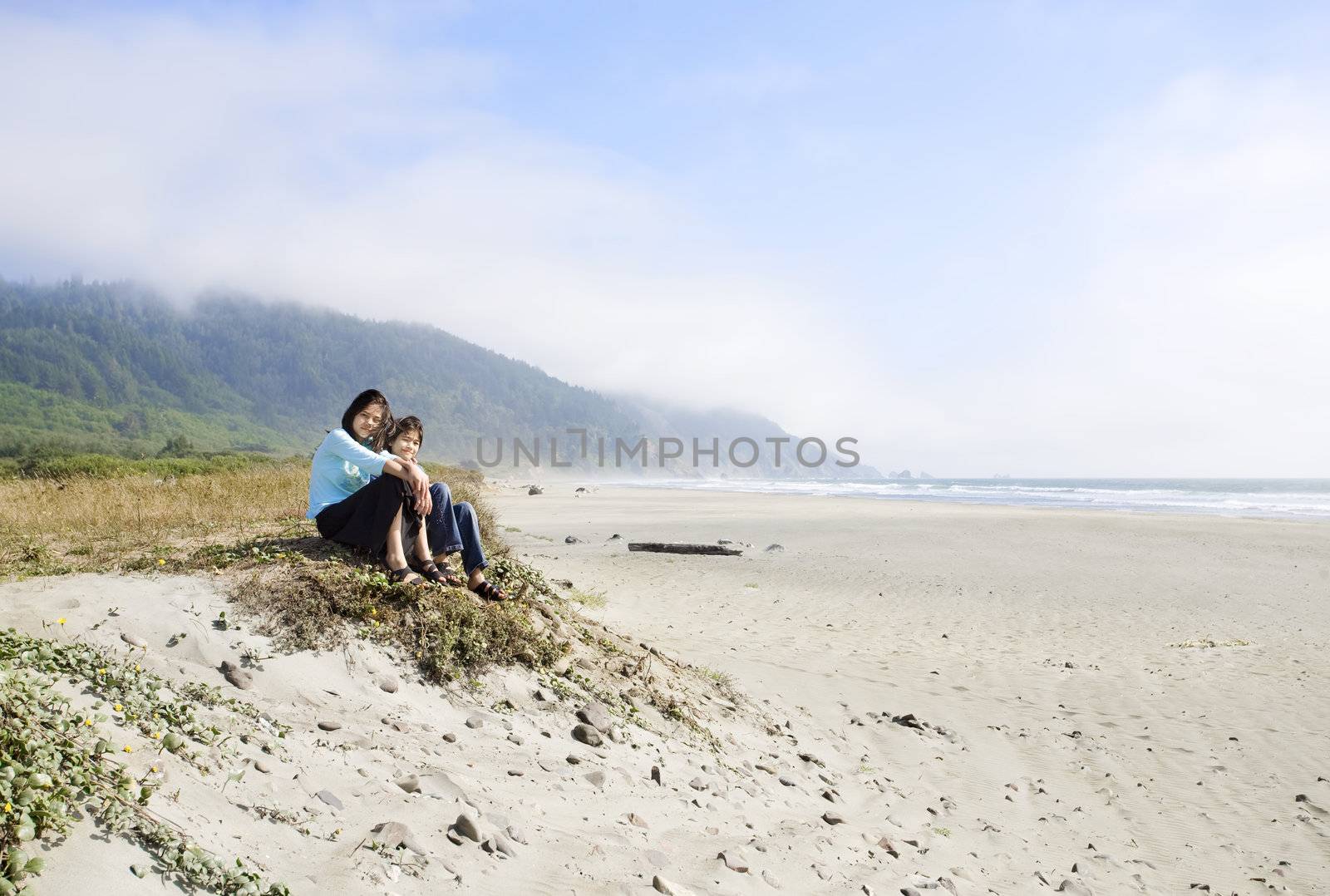 Two young girls enjoying the beach by the ocean shore