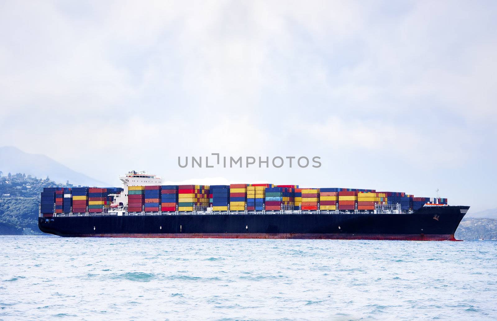 Large cargo ship in water carrying colorful shipping containers by jarenwicklund