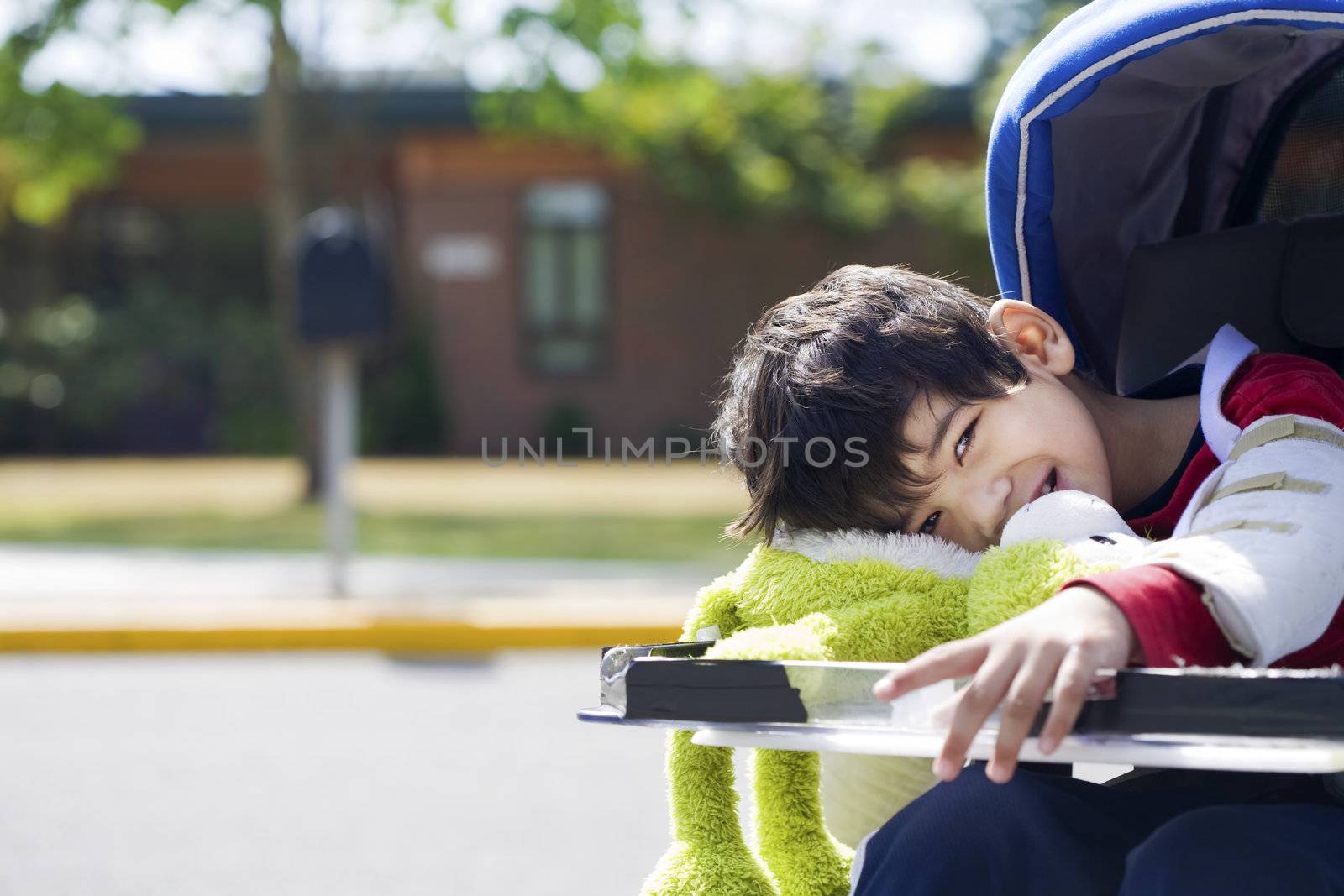 Disabled five year old boy in wheelchair in front of school