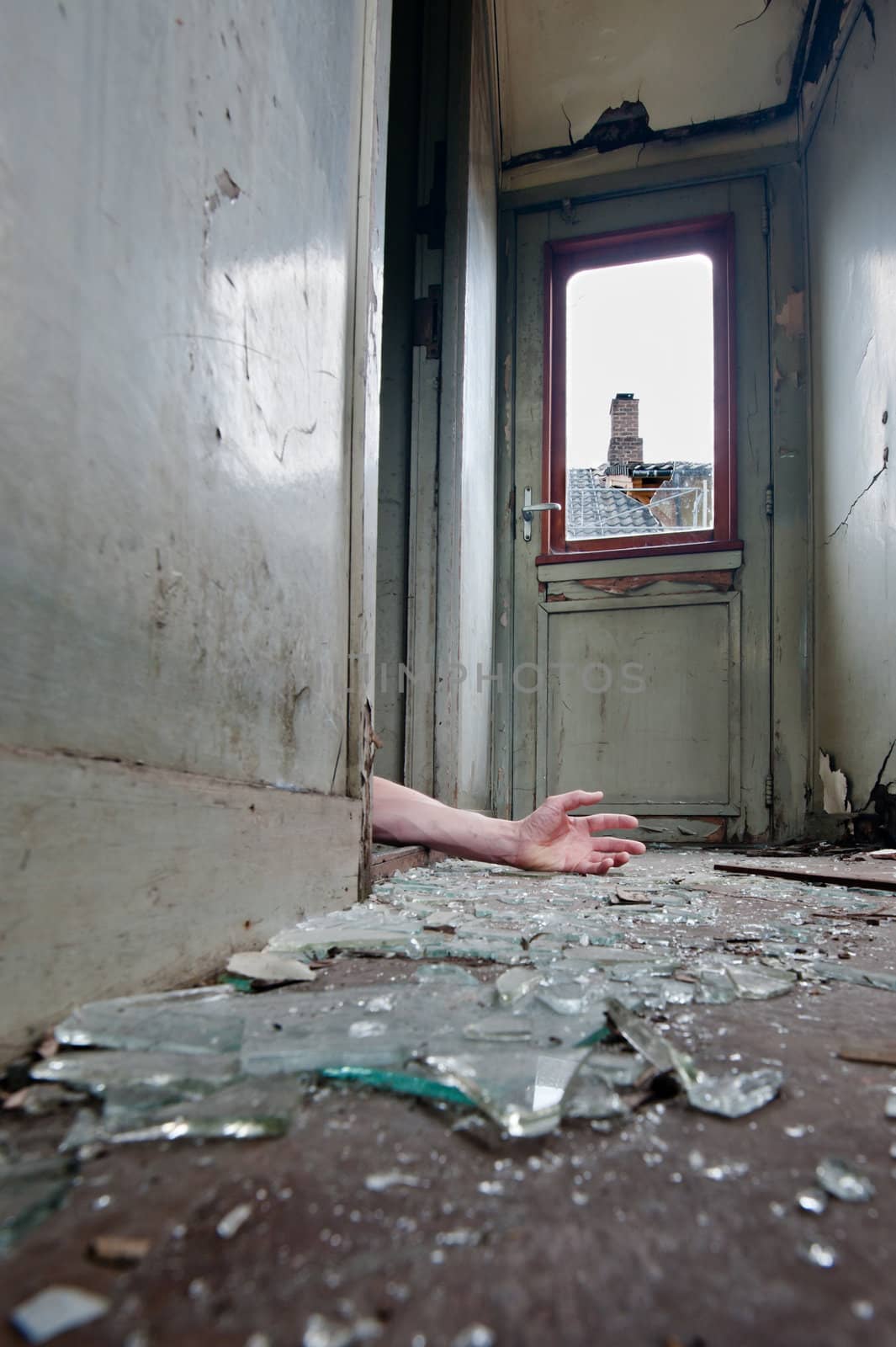 A person lying on the floor inn an old worn-out railway carriage with broken glass on the floor