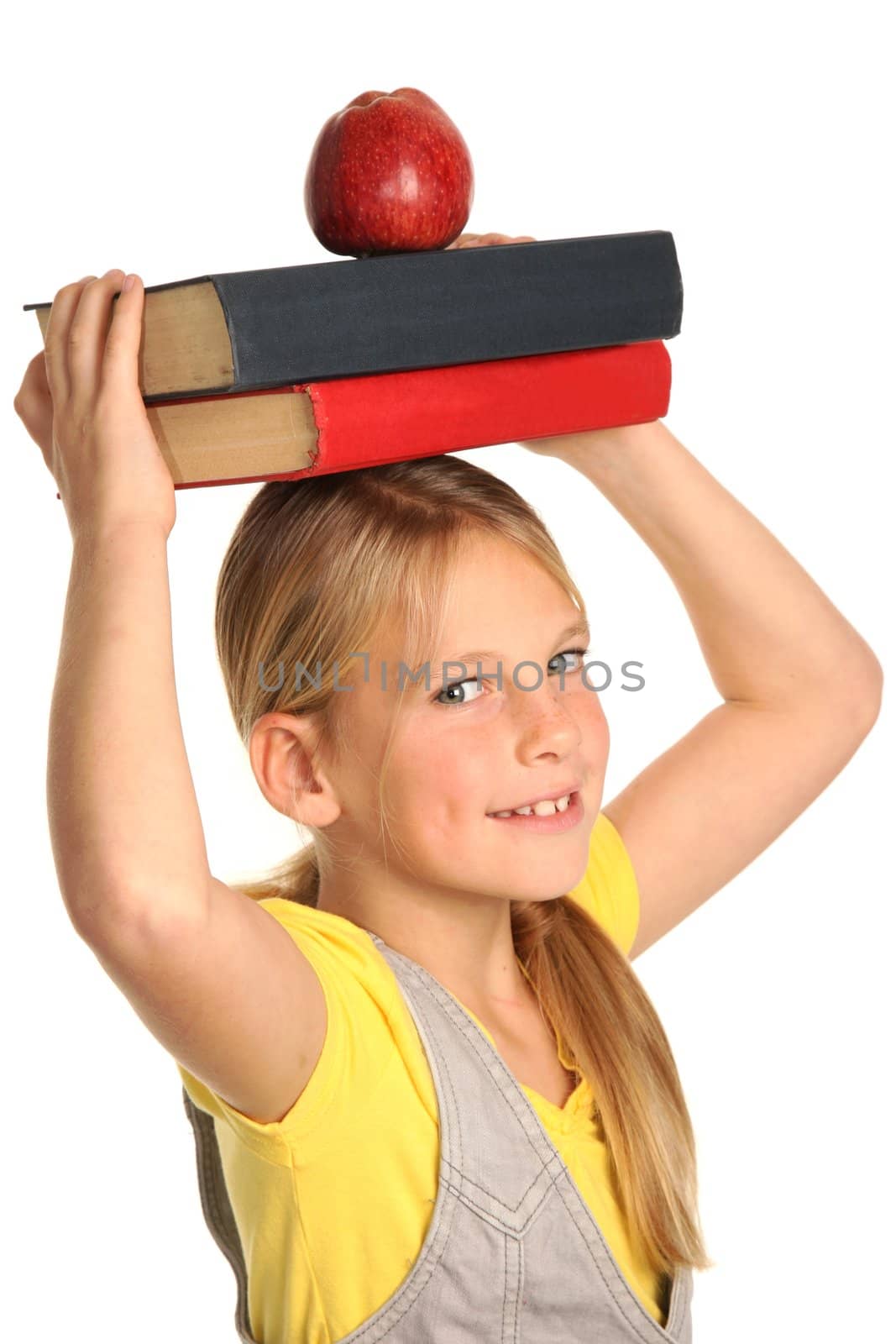 Pretty young student blond kid with books and red apple on her head
