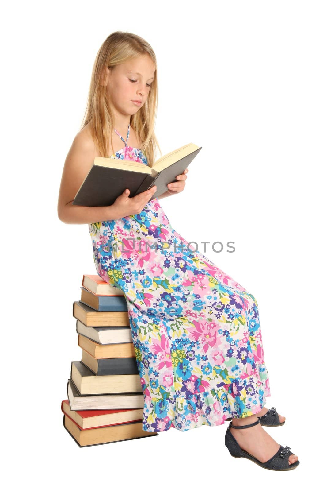 Beautiful young school girl sitting on a pile of books and reading