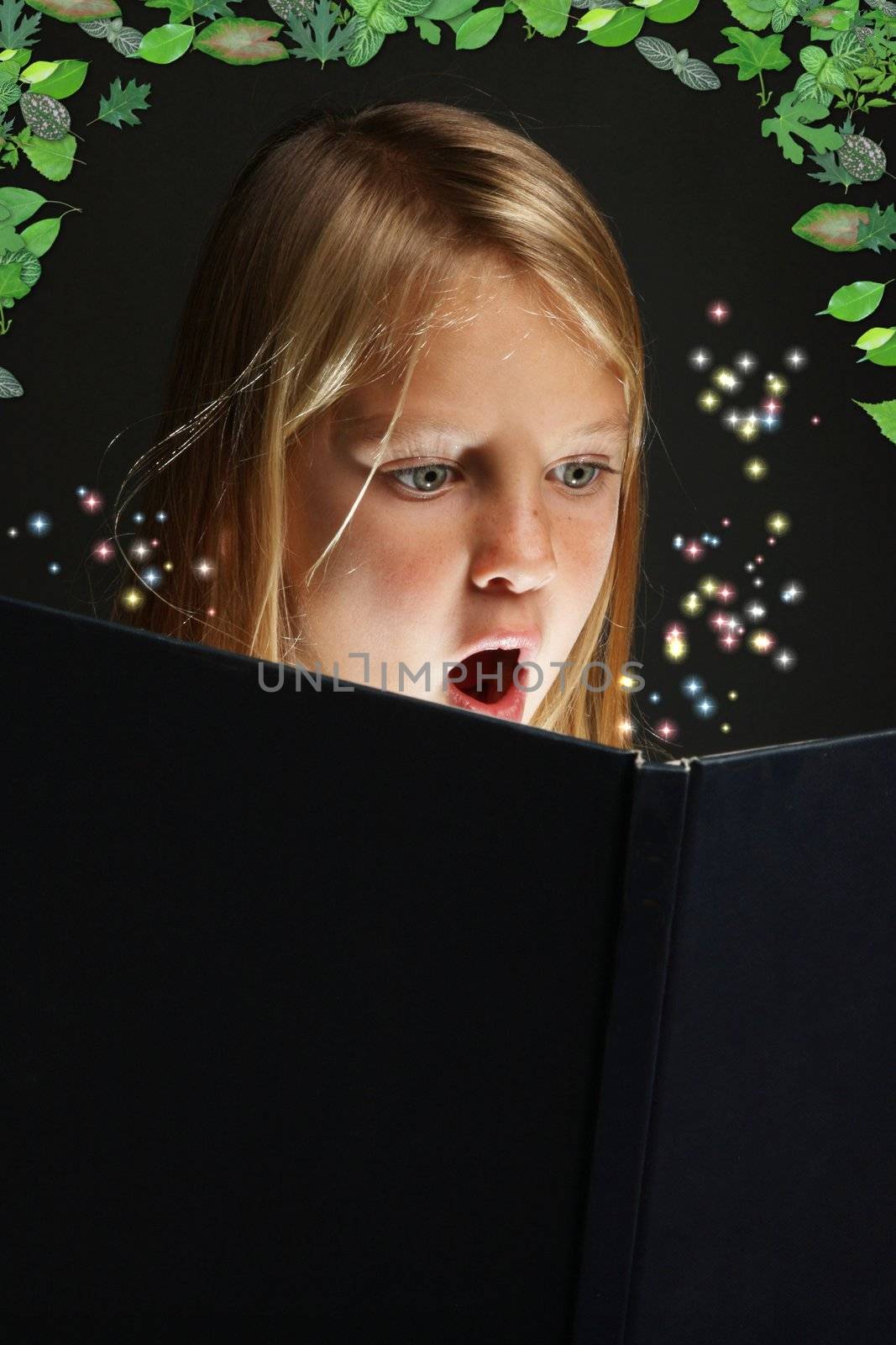 Pretty young school girl engrossed in reading a book with stars coming out of it