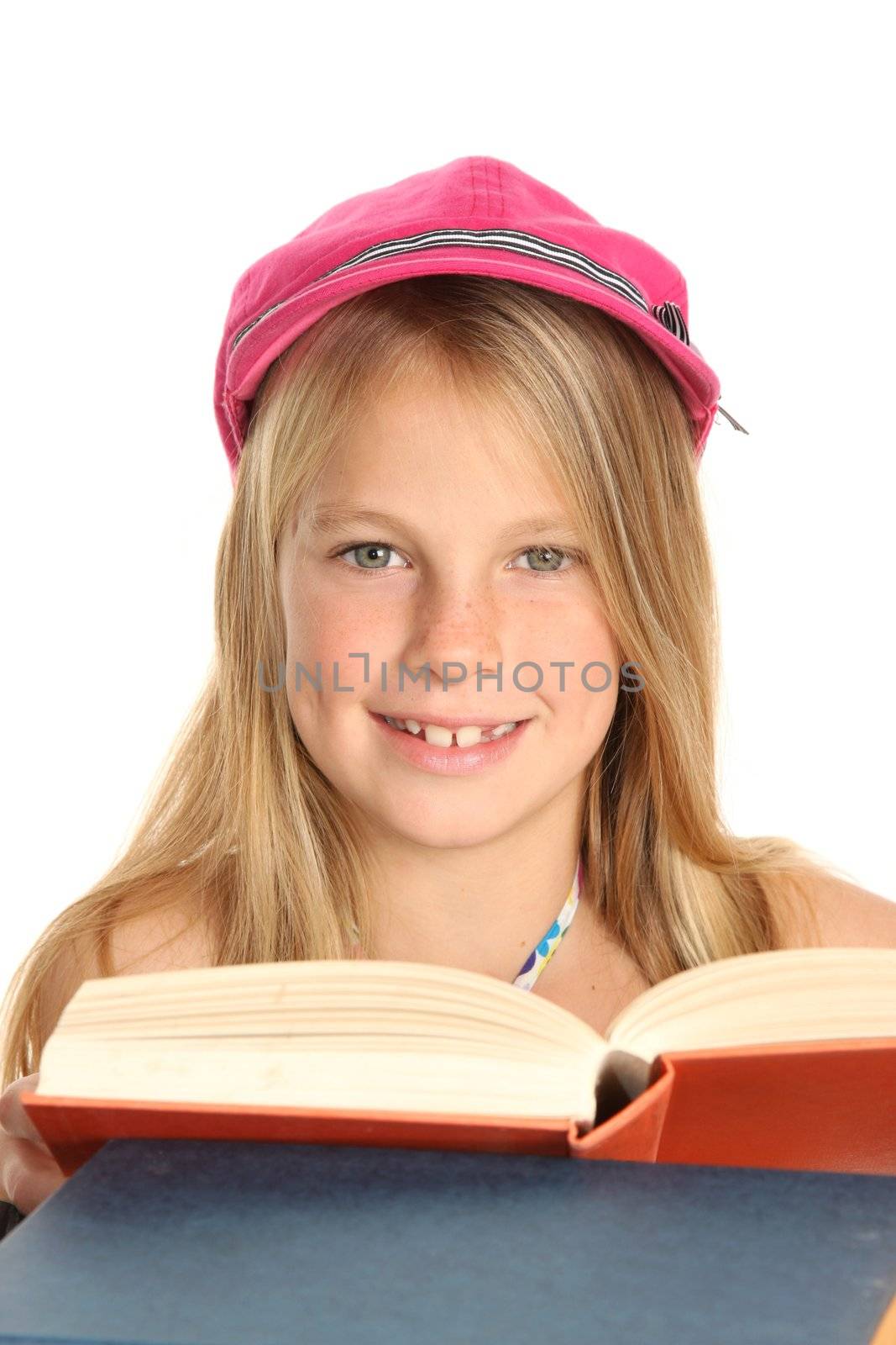 Pretty young school girl in pink cap reading books