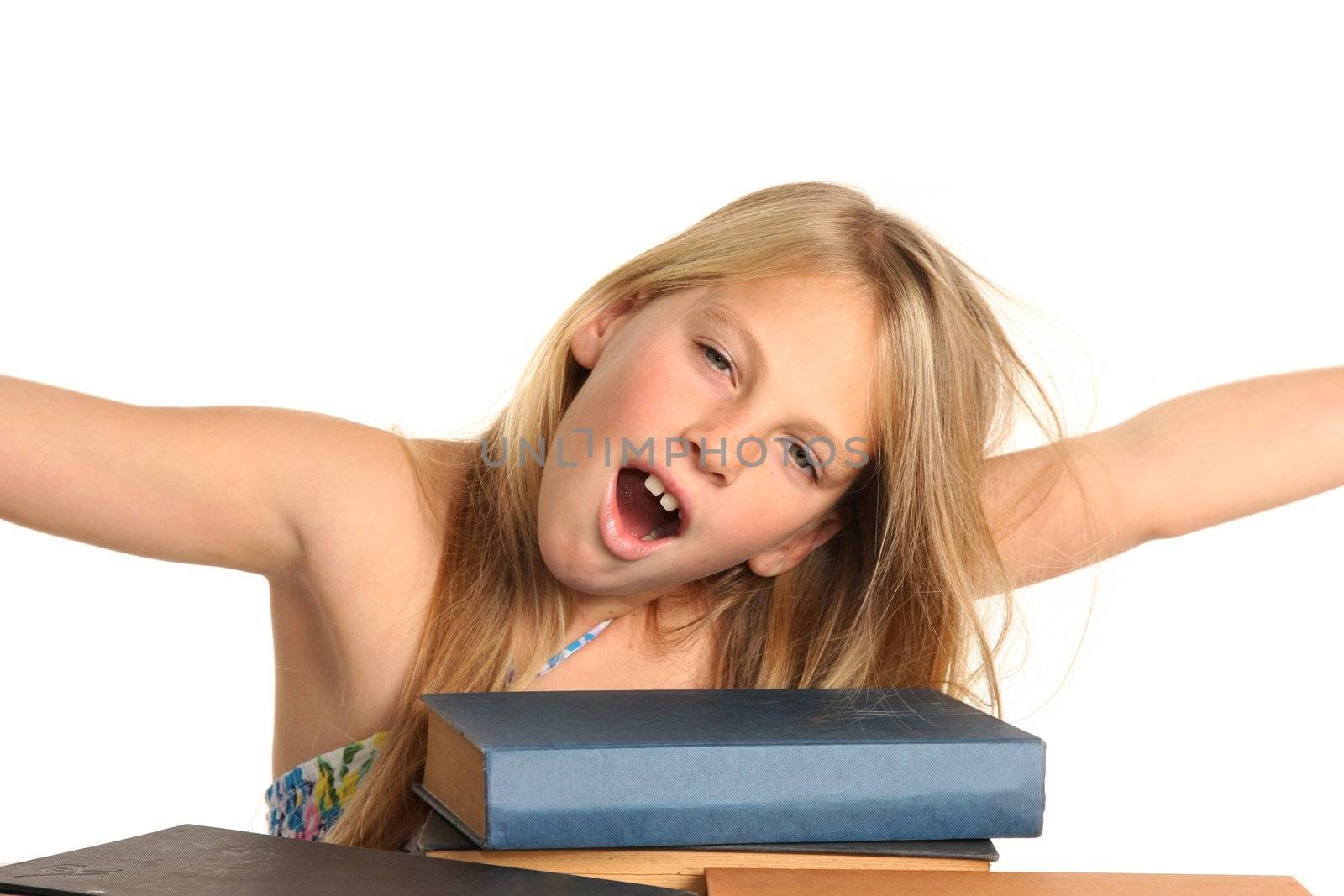 Pretty preteen blond girl yawing and stretching with pile of books in front of her