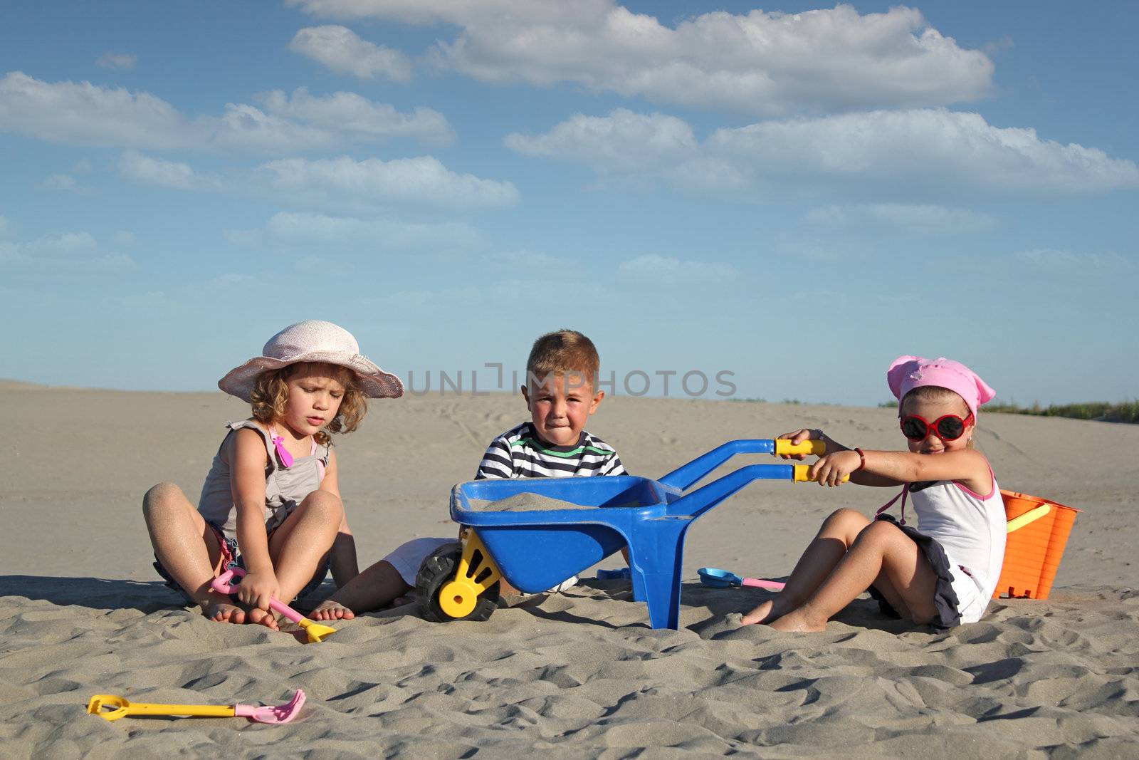 three children playing in sand by goce