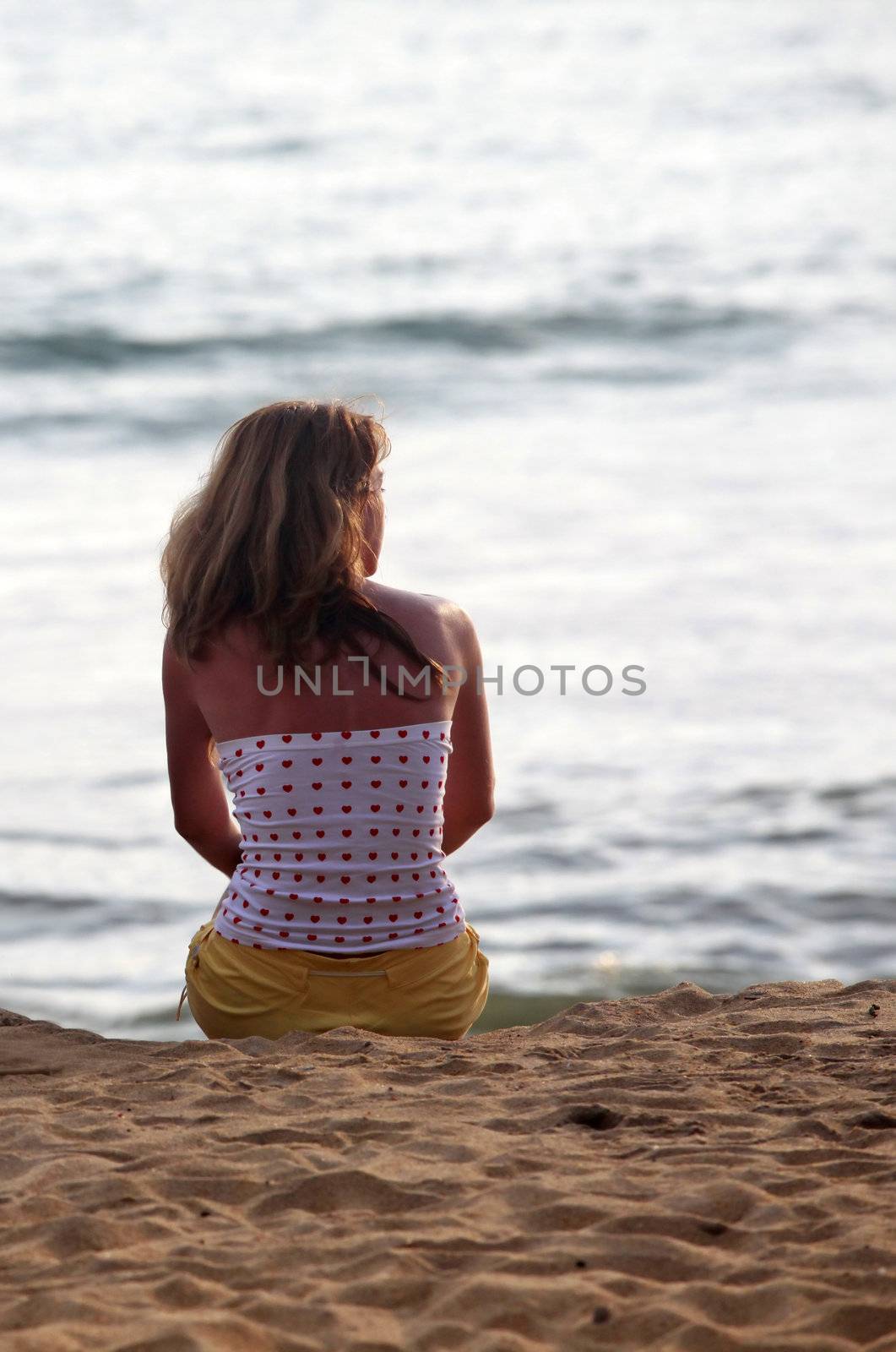 The girl on coastline ocean admires a sunset