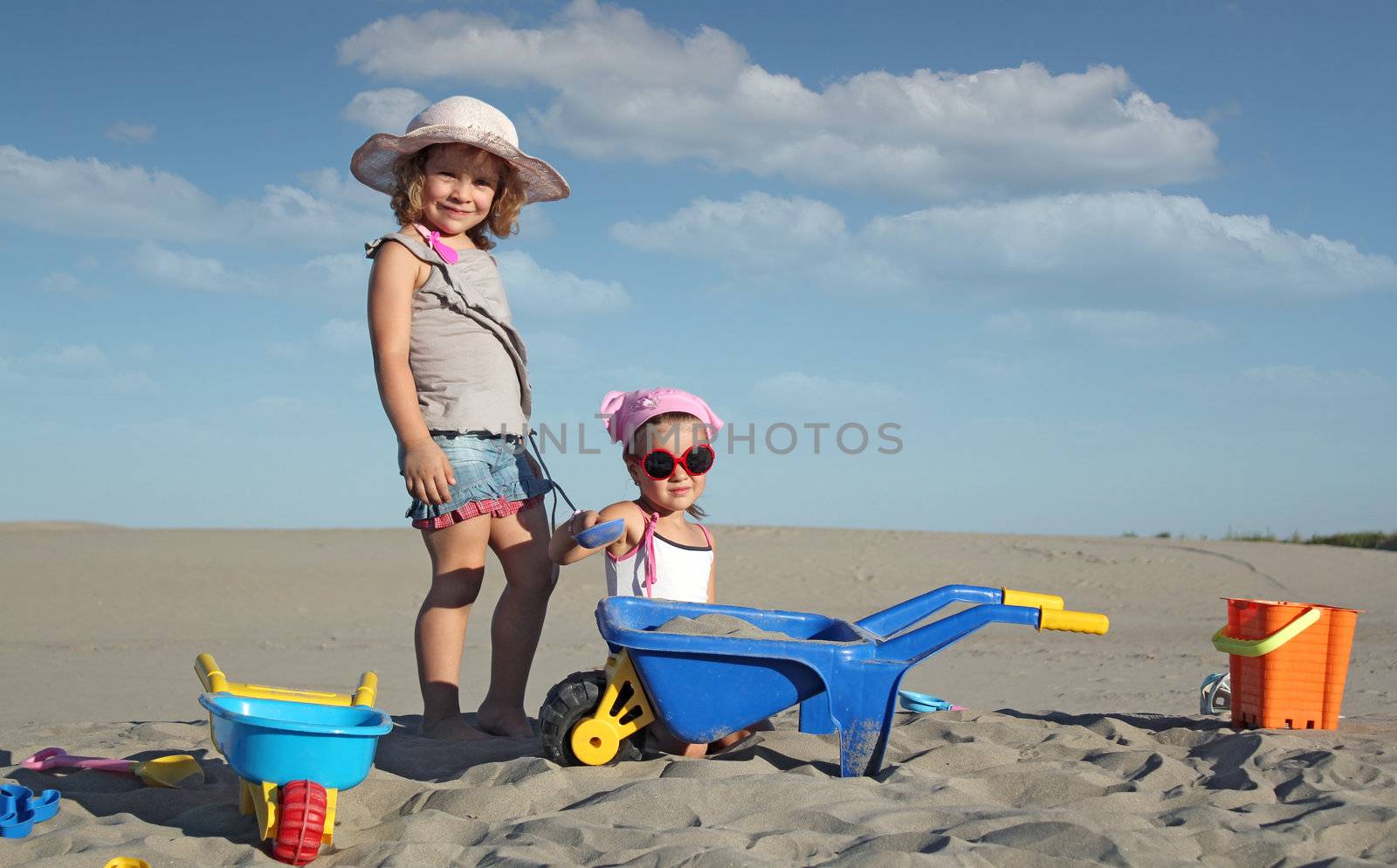 two little girl fun and play in sand by goce