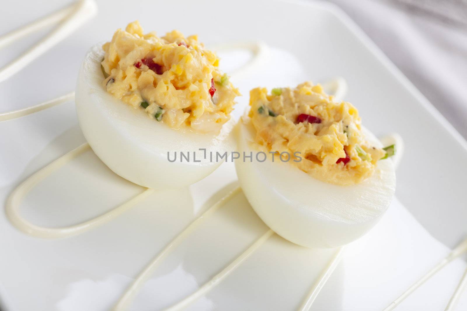 Two gourmet deviled eggs on white plate