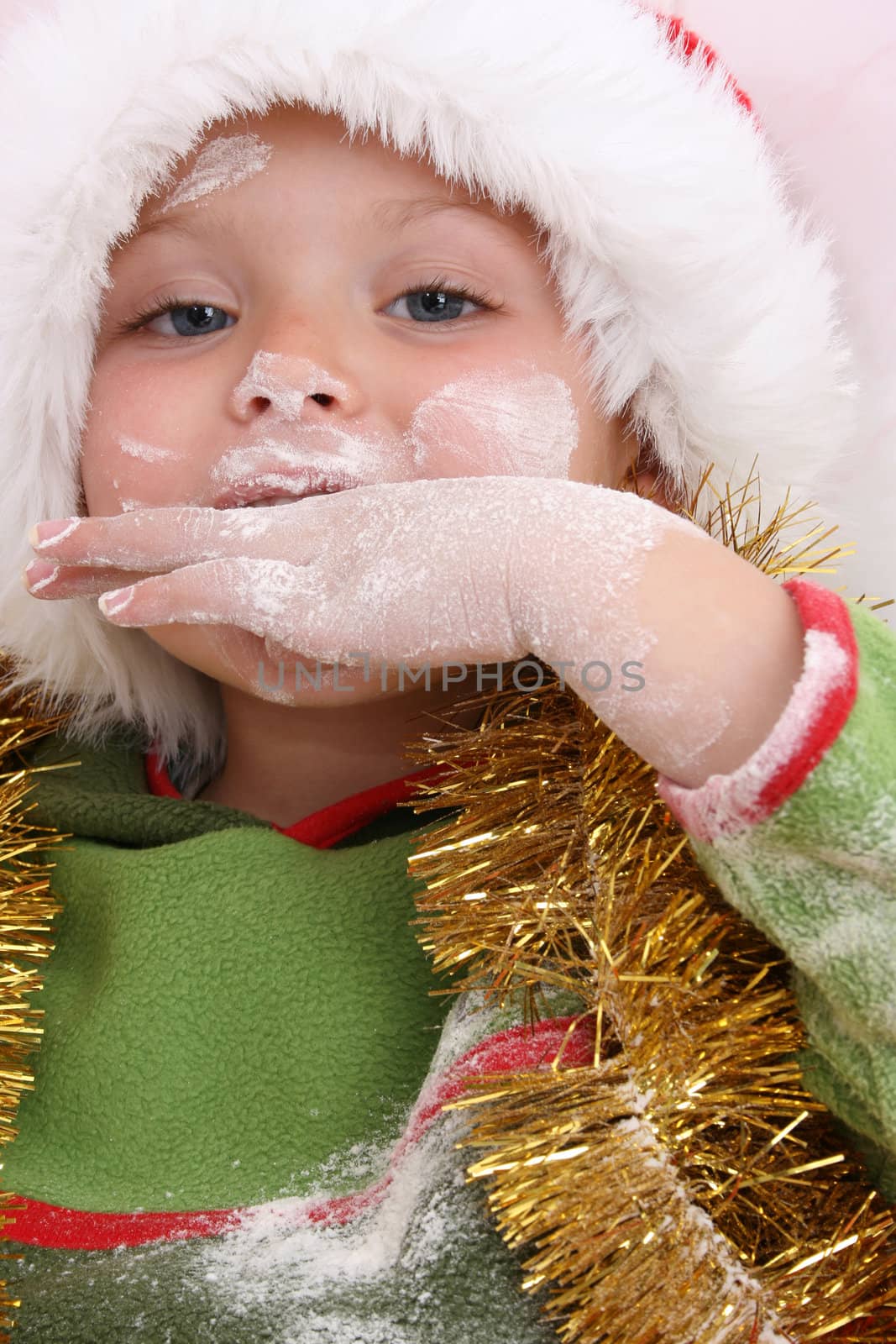 Toddler wearing a christmas hat, baking christmas cookies
