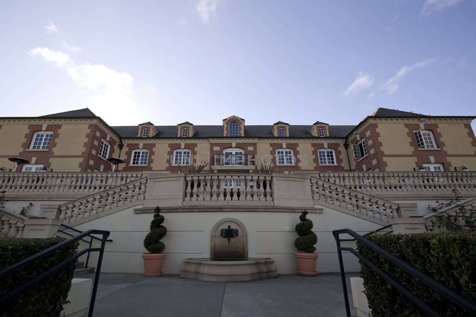 A very large old estate at the top of a hill with several windows