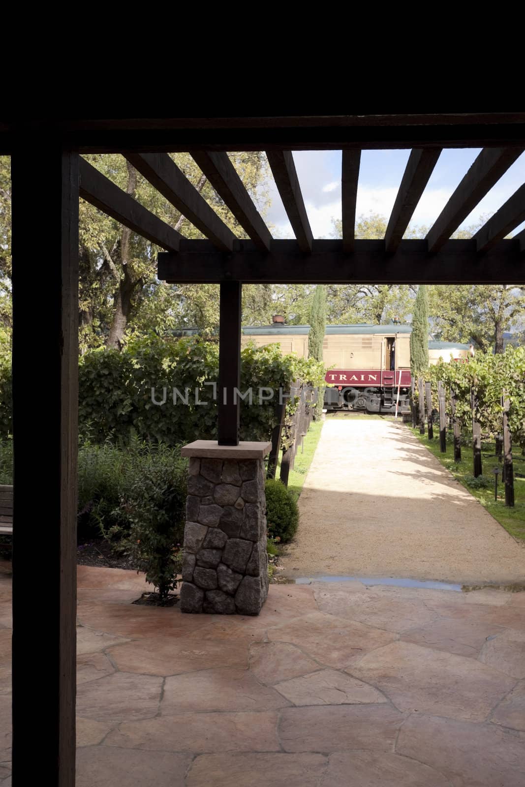 A trellis framing a beautiful landscaped view of a train in the distance