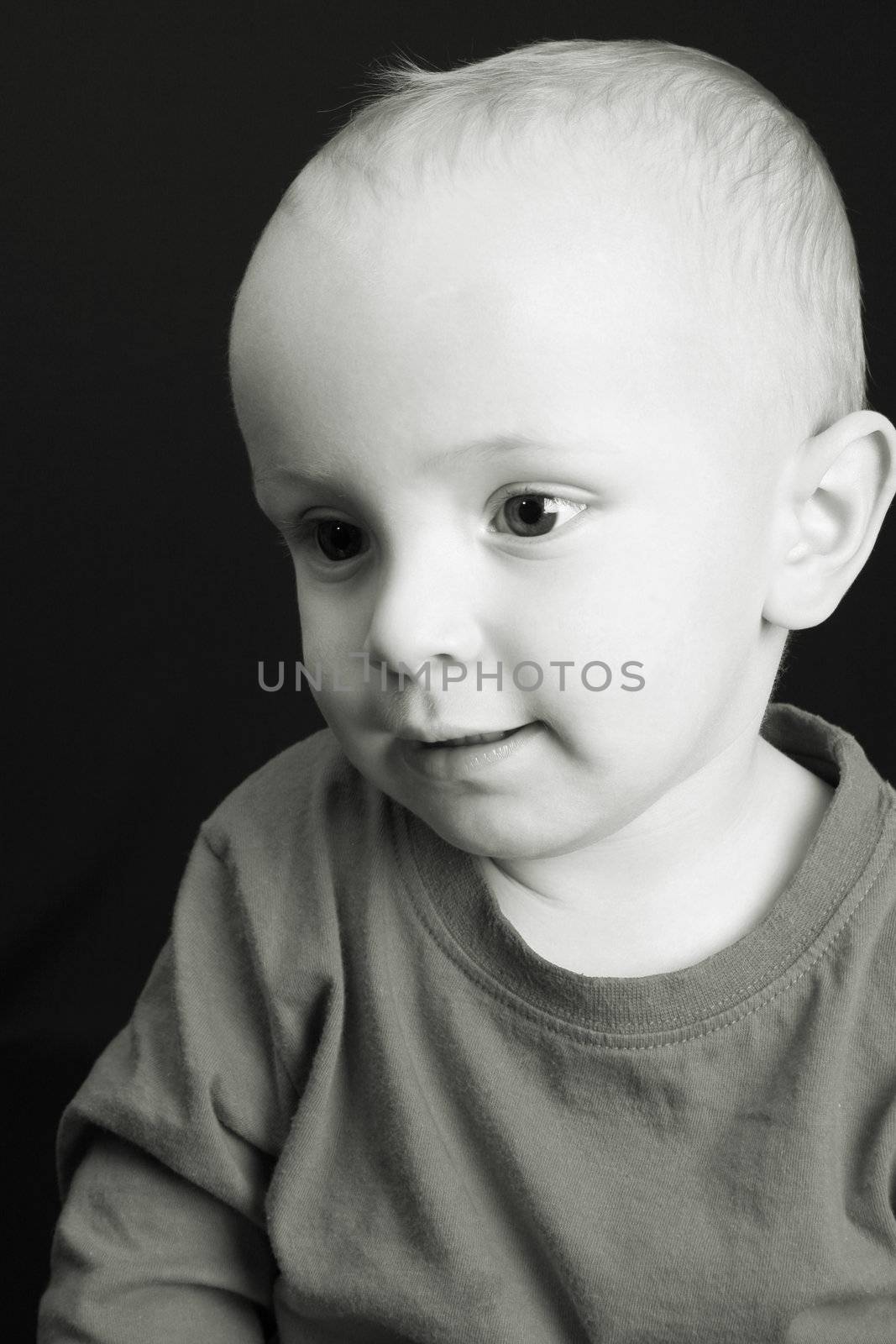Sepia toned image of a little toddler boy on black background