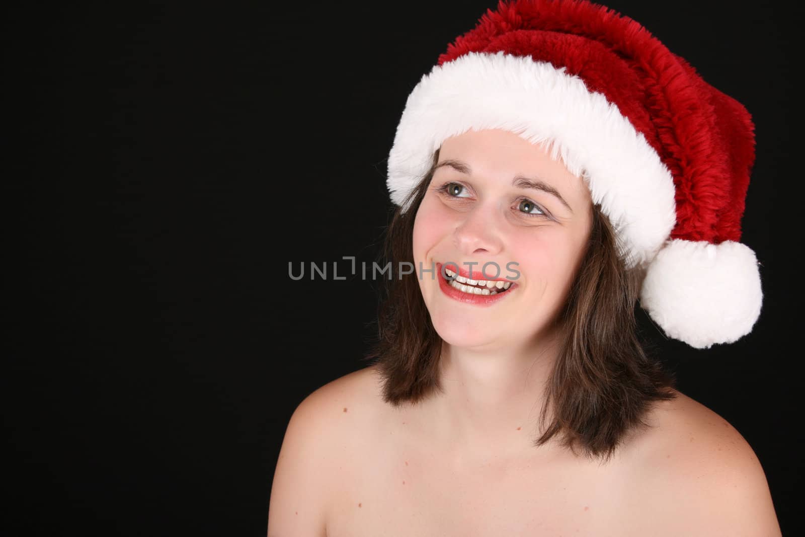 Beautiful brunette female wearing a christmas hat against a black background