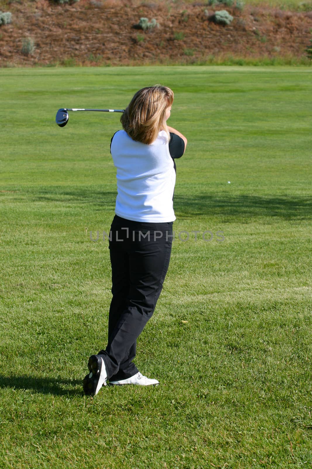 Blond female golfer playing a shot from the fairway