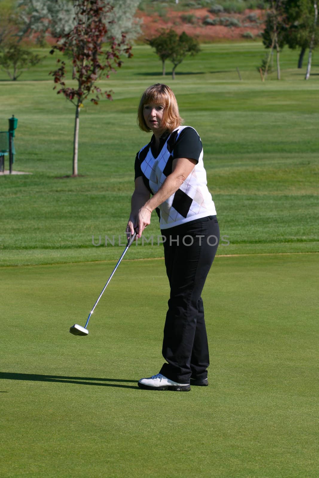 Blond female golfer putting on the green