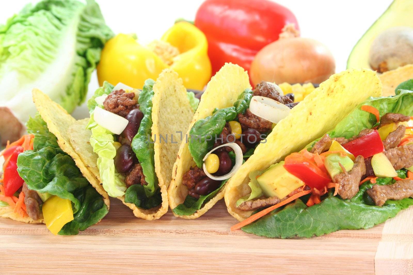 Mexican tacos with beef, ground beef, lettuce, red kidney beans and corn, peppers and avocado