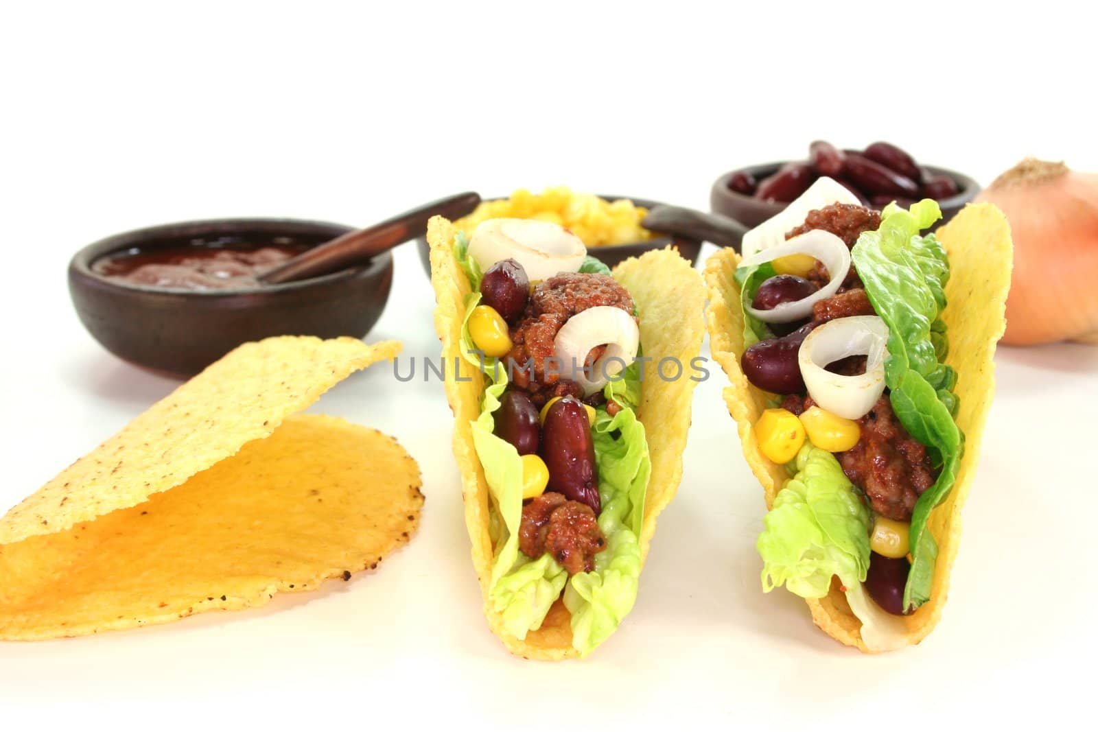 Mexican tacos with ground beef, lettuce, red kidney beans and corn on a white background