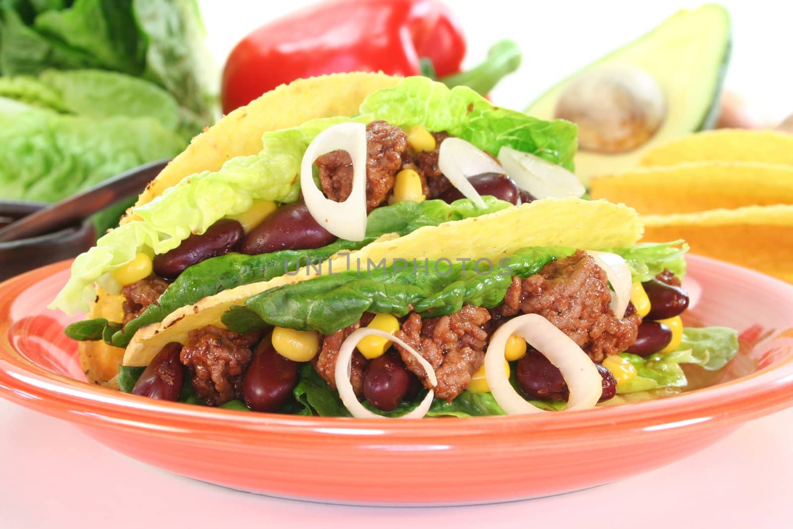 Mexican tacos with ground beef, lettuce, red kidney beans and corn on a white background