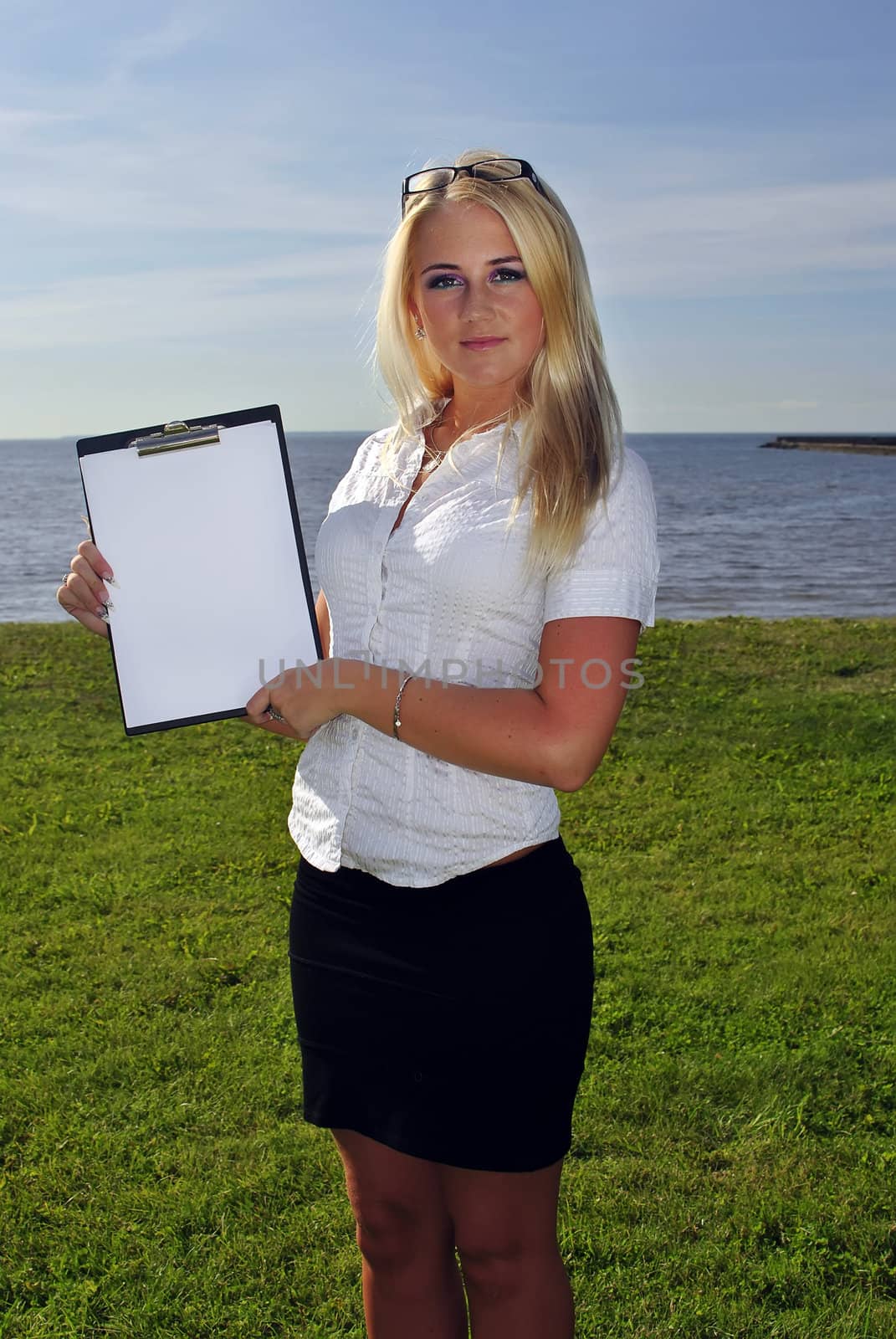 Girl holding a blank paper against the sea. Space for writing a text.