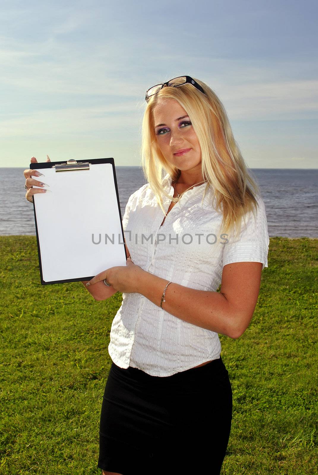 Girl holding a blank paper against the sea. Space for writing a text.