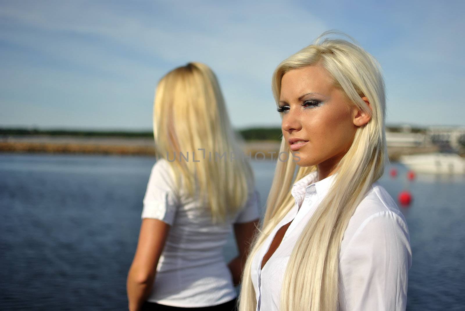 Two blonde girls on the beach. One is blurred. Out of focus.