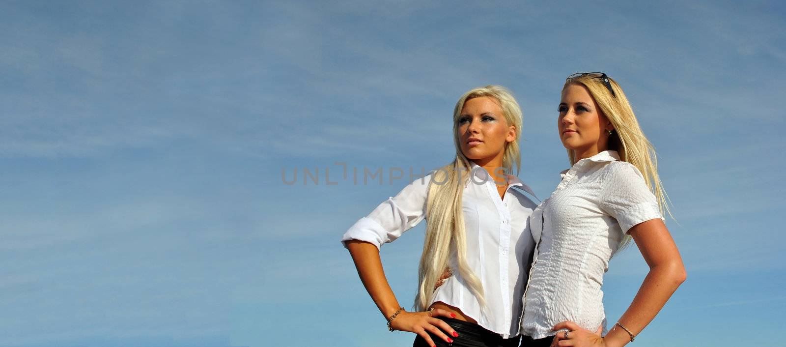 Two blonde girls on sky background. Perfect for placing your own advertisements on