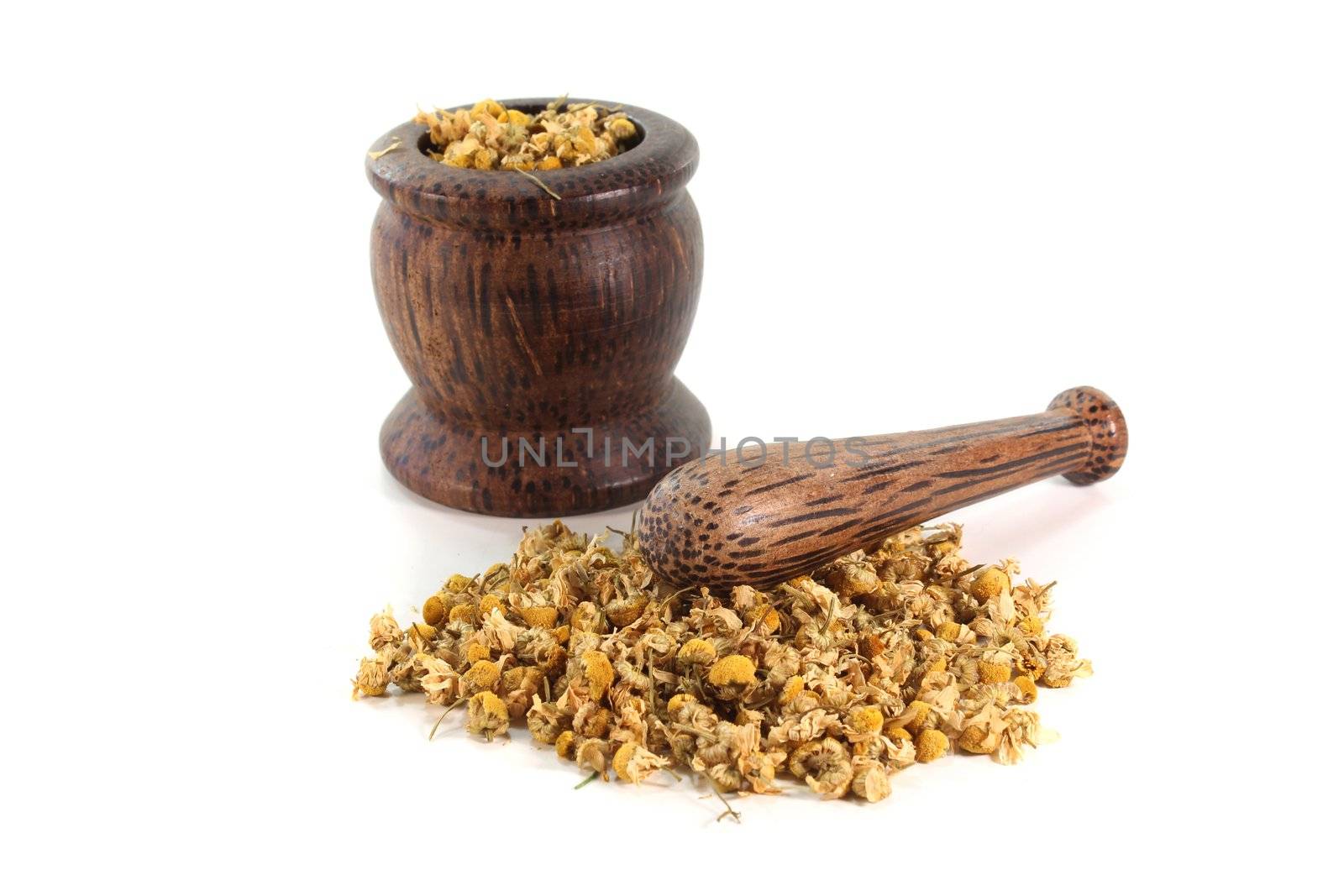 dried chamomile flowers with a mortar on a white background