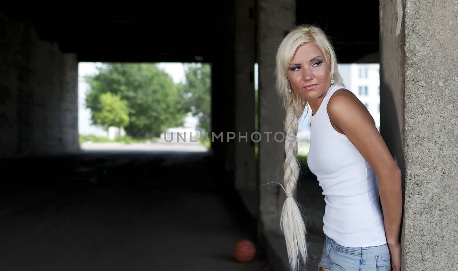 athletic girl in denim shorts and white T-shirt standing at the pillar