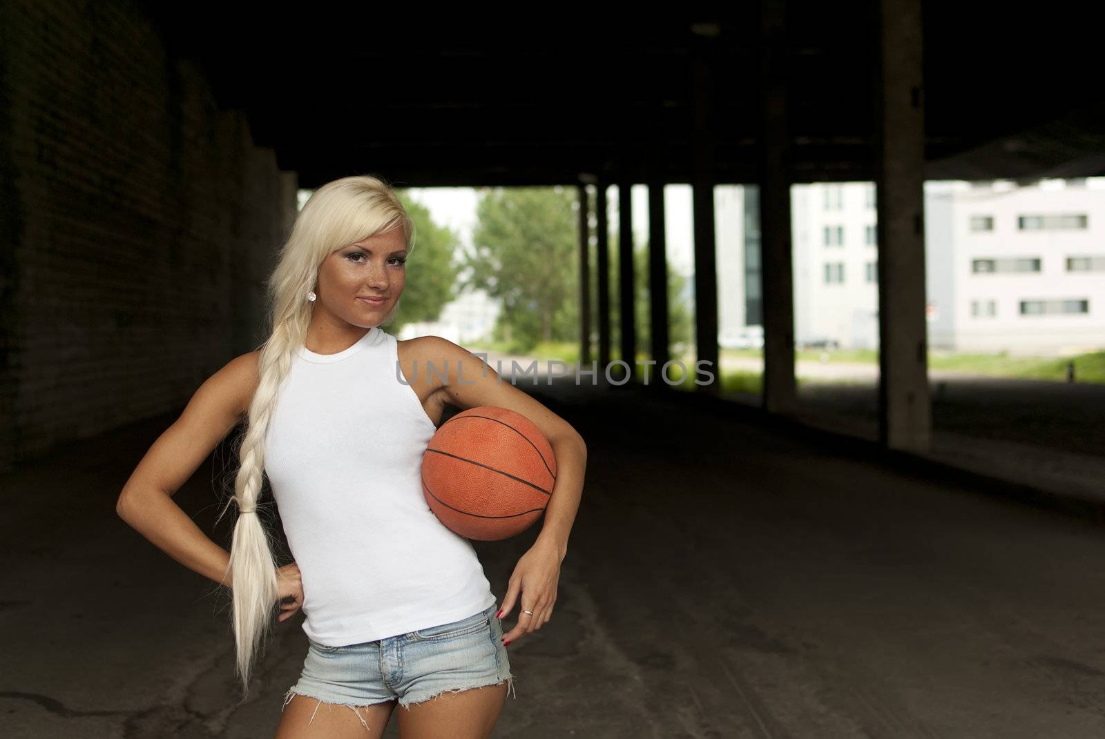 Beautiful blonde girl standing with basketball in the street