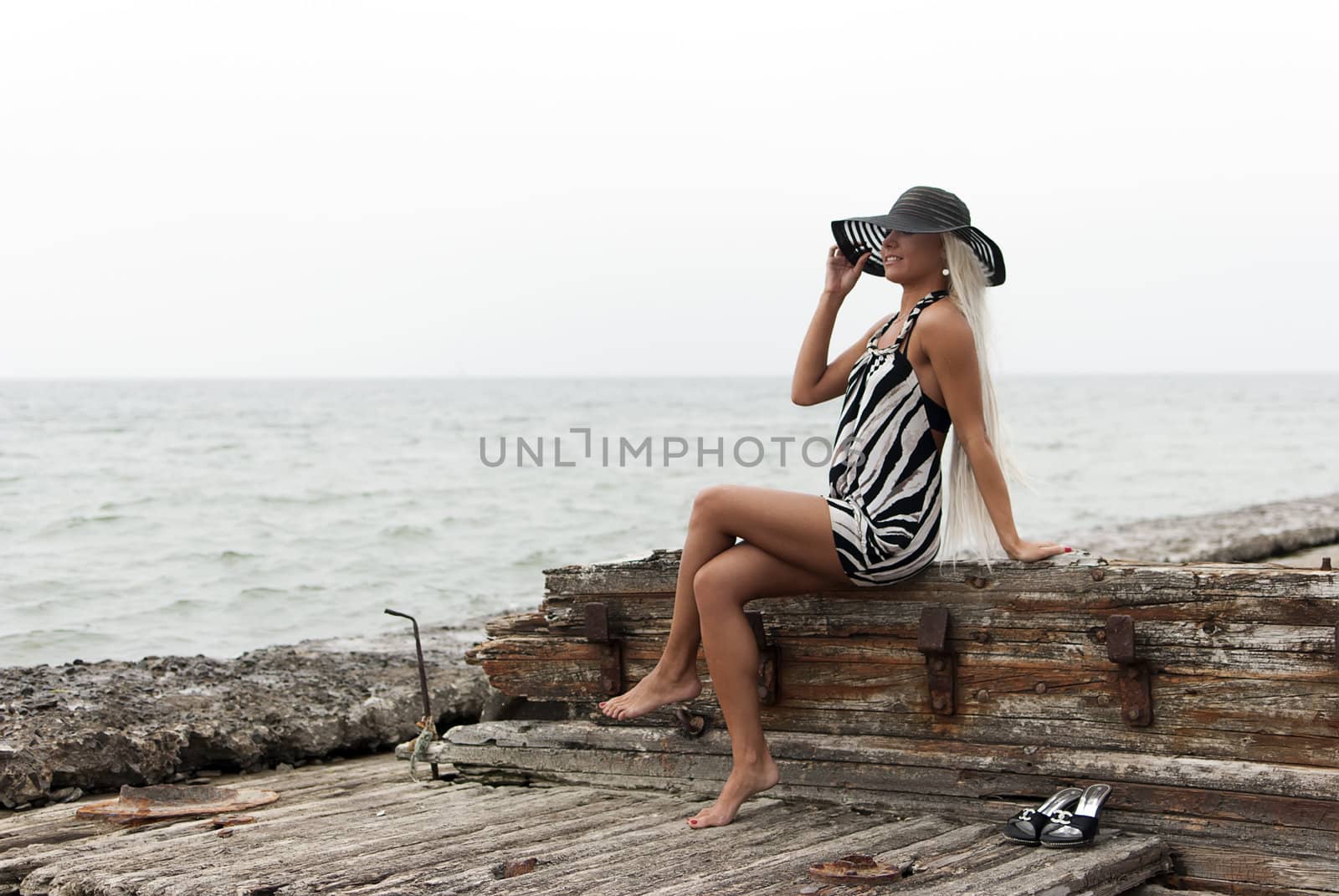 girl in a hat sitting on a broken ship at sea